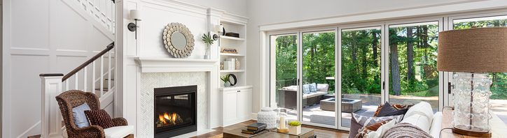 Beautiful living room interior with hardwood floors and fireplace in new luxury home with sliding glass doors and vaulted ceiling